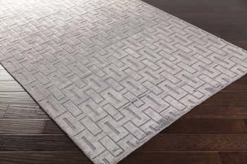 Close-up of the hand-knotted Voca Area Carpet. Contemporary style rug with a geometric pattern and soft gray color. Corner