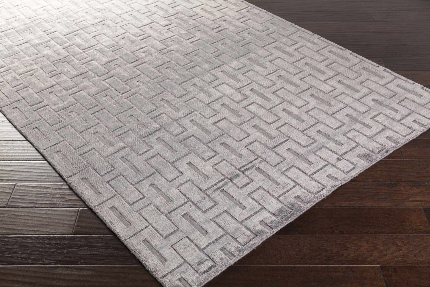 Close-up of the hand-knotted Voca Area Carpet. Contemporary style rug with a geometric pattern and soft gray color. Corner