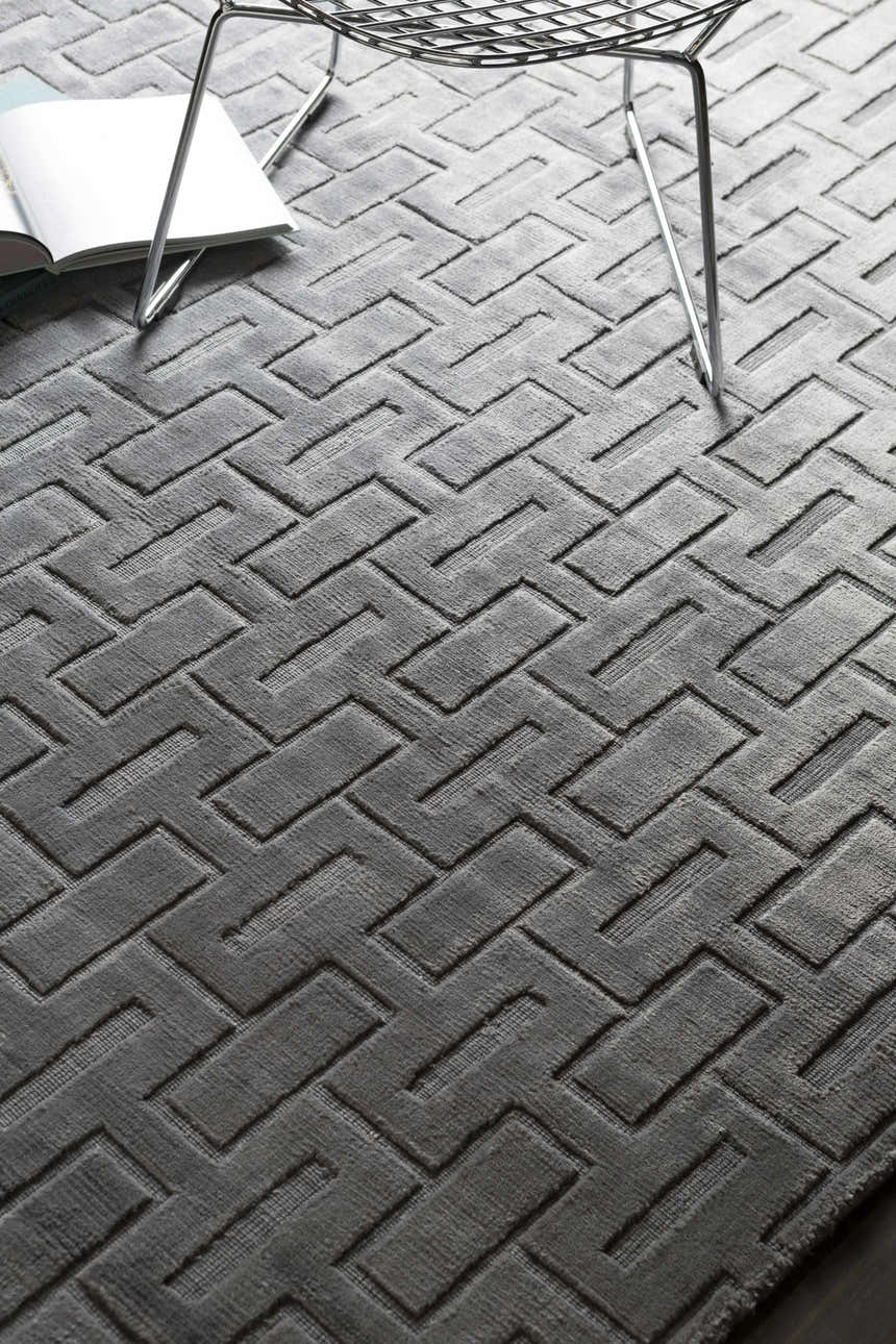 Close-up of the Voca Area Carpet, a hand-knotted, contemporary rug with a gray geometric brick pattern and soft viscose texture. Styleshot