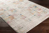 Close-up of the Eversley Area Rug. Cream rug with dark blue, dark pink, mustard, and saffron accents. Corner