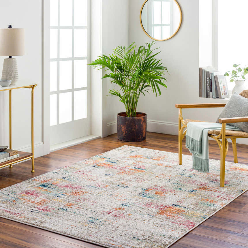 Living room scene with the Eversley Area Rug, gold accents, a plant, and a chair with a throw. Roomscene-Rectangle