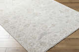 Close-up of the Vaman Luxe Rug in light silver and sterling gray with a traditional floral pattern on wood floors. Corner