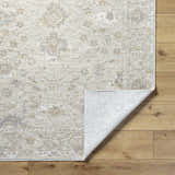Close-up of the Vaman Luxe Rug showing its light silver and sterling gray traditional floral pattern and machine-woven texture. Fold