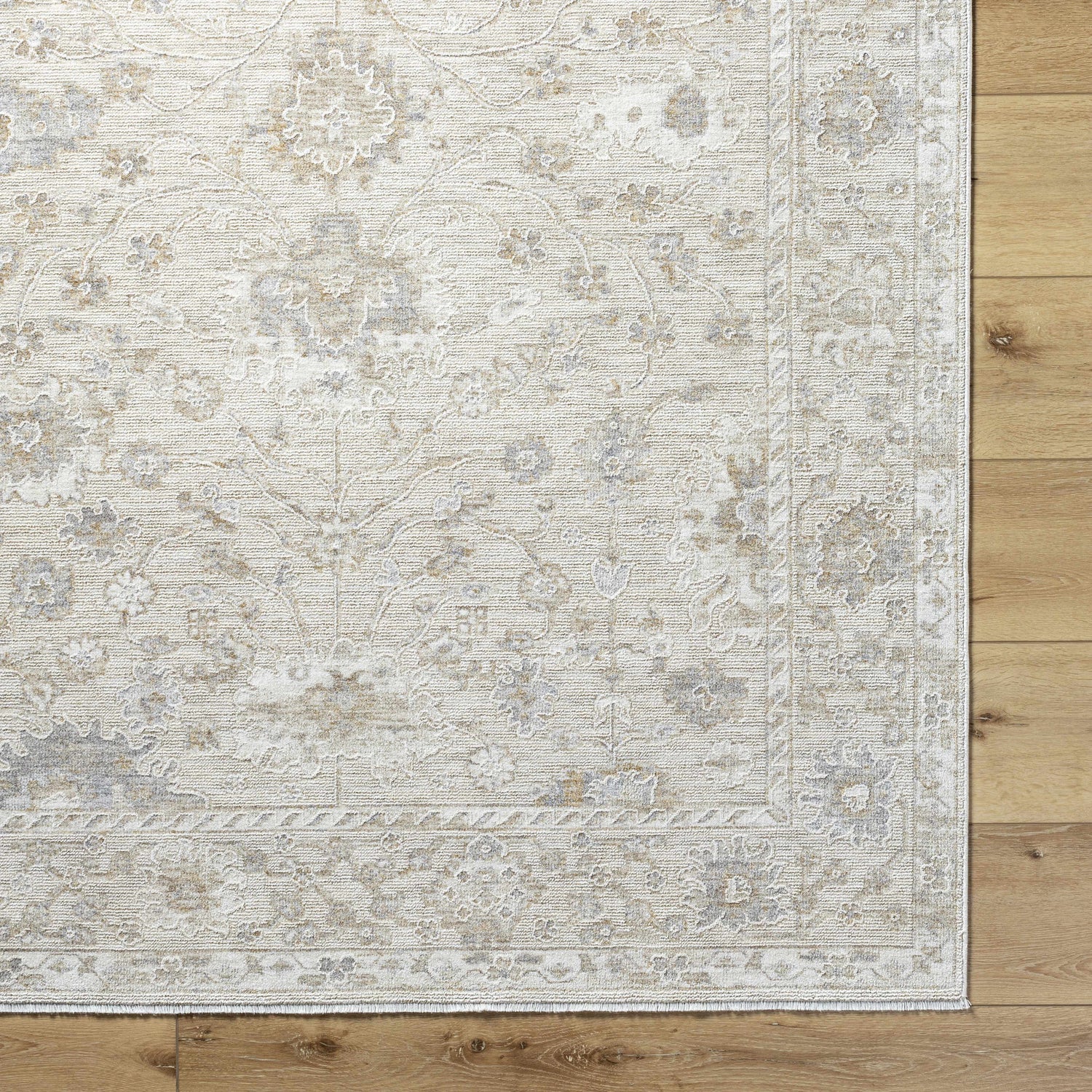 Close-up of the Vaman Luxe Rug in light silver and sterling gray, featuring a traditional floral pattern. Corner