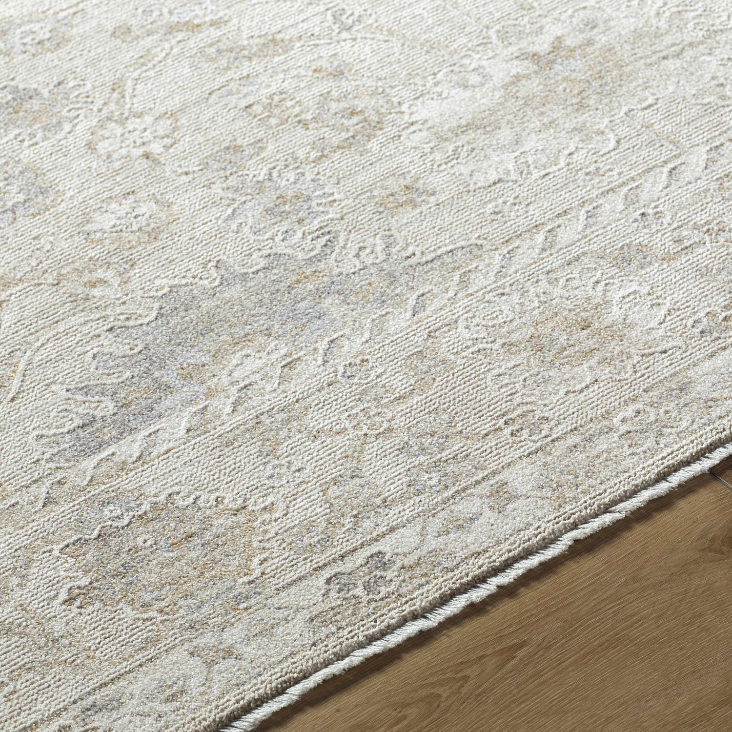 Close-up of the Vaman Luxe Rug. Light silver and sterling gray tones with a traditional, subtle floral pattern. Machine woven texture. Texture