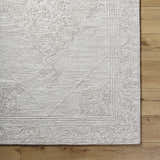 Close up of the hand tufted Verne Area Rug in ash, showing the wool texture and traditional pattern. Corner