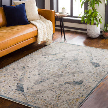 Living room scene with a blue and mustard Wadeye Luxe Fringe Rug, tan leather sofa, and wood floors. Roomscene-Rectangle