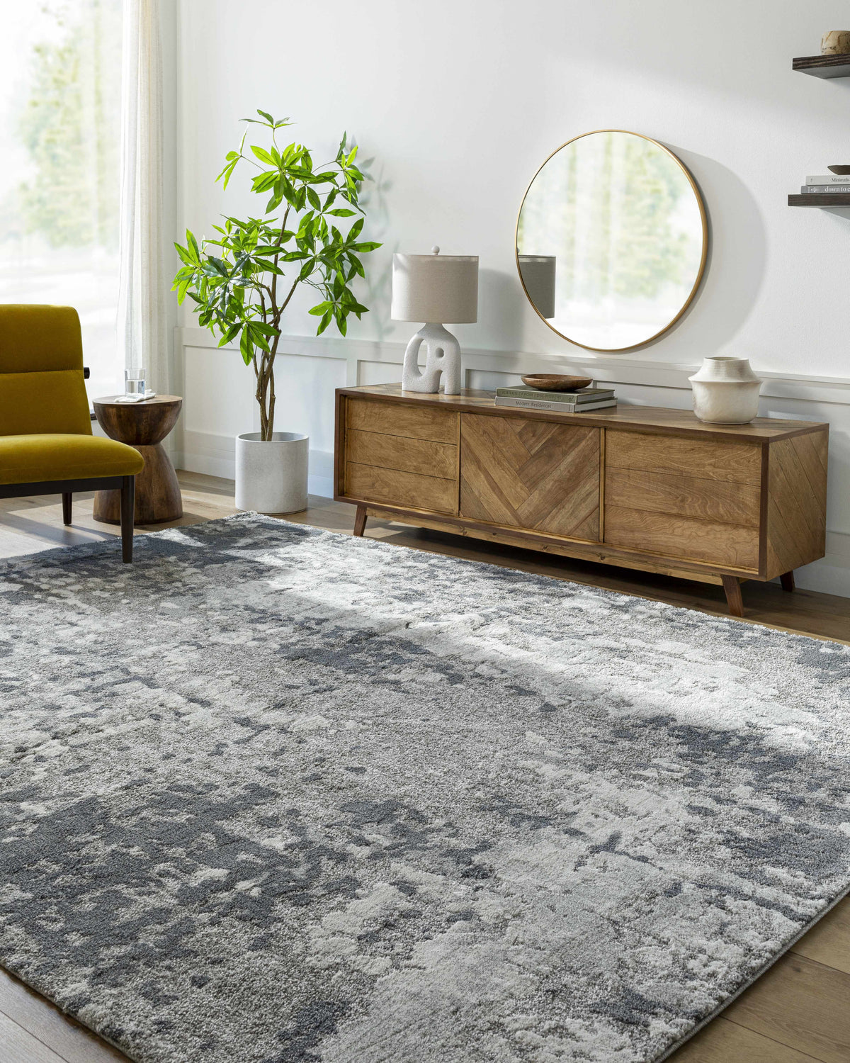 Living room scene with a gray and ivory Walhonding Area Rug, wood cabinet, round mirror, and yellow accent chair. Roomscene-Rectangle