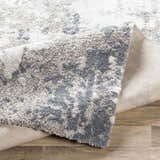 Close-up of the Walhonding Area Rug, a contemporary design in denim, ivory, and gray. Machine-woven texture detail. Fold