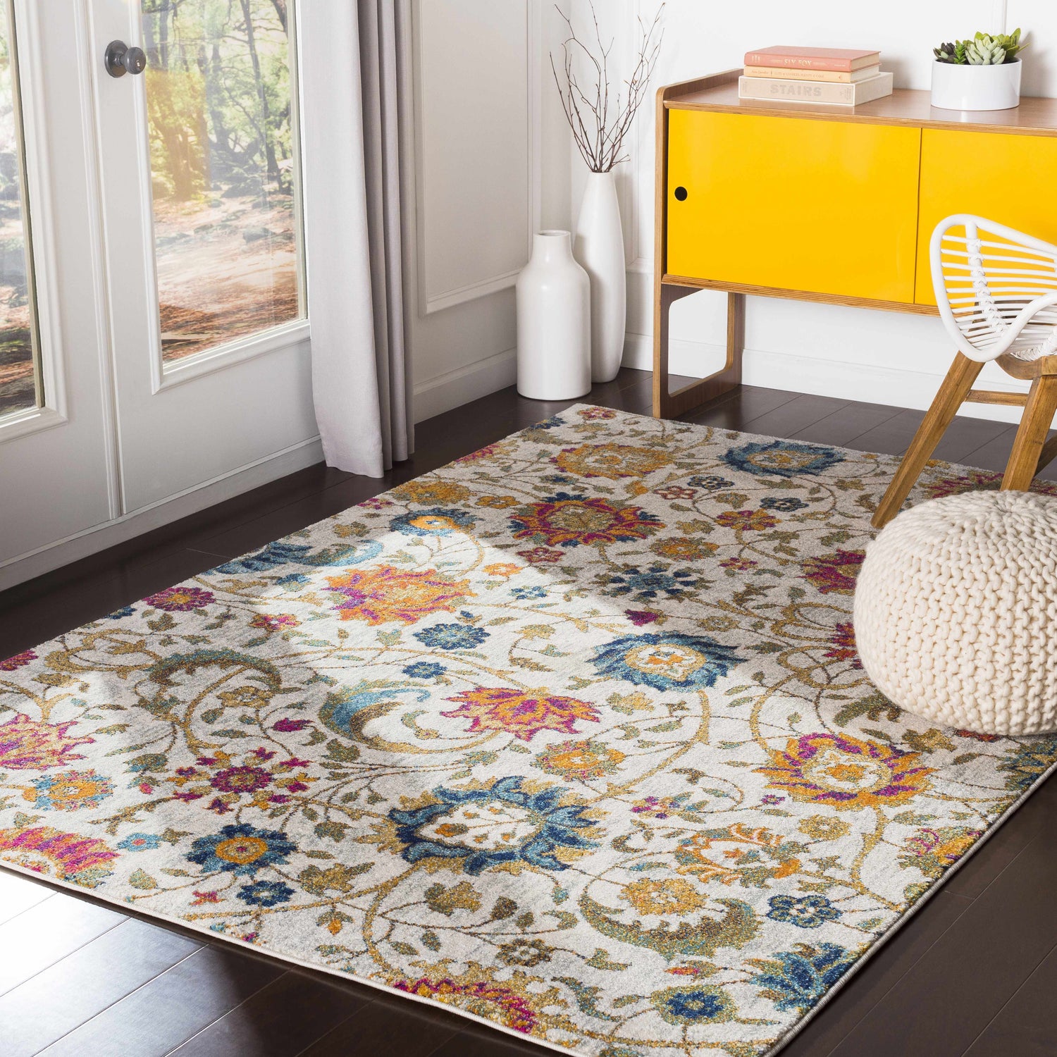 Bright living room with Walsenburg Floral Rug, yellow cabinet, white chair and pouf. Roomscene-Rectangle