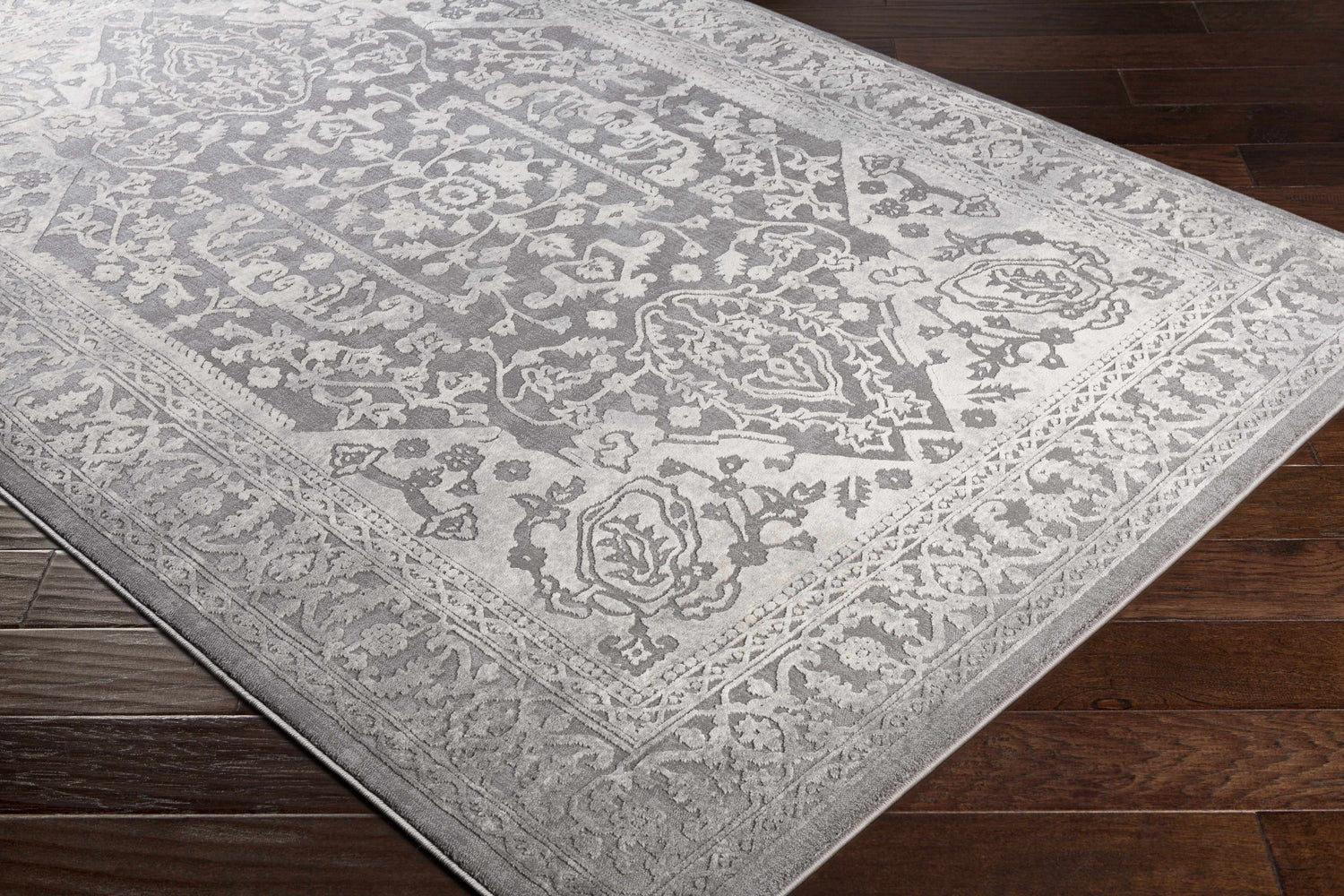 Close-up of the Watford Updated Traditional Tibetan Rug. Gray and ivory floral pattern on a charcoal background. Corner