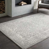 Living room scene with a gray Watford Updated Traditional Tibetan Rug, fireplace, dark wood floors, and gray chair. Roomscene-Rectangle