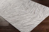 Close up of Wauzeka Premium Area Rug showing cream, brown and gray tones with a geometric pattern on dark wood floor. Corner