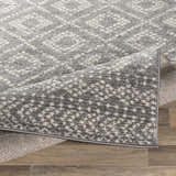 Close-up of the Webb Area Rug, showing its charcoal, gray, and white bohemian pattern and machine woven texture. Fold