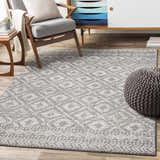 Living room scene with gray armchair, pouf, and geometric Webb Area Rug in charcoal, gray, and white. Roomscene-Rectangle