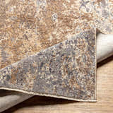 Close-up of the Woodmoor Area Rug. Bone, dark gray, eggplant, walnut, and white thatch colors in a contemporary pattern. Fold
