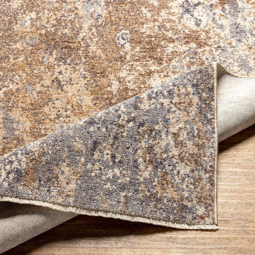 Close-up of the Woodmoor Area Rug. Bone, dark gray, eggplant, walnut, and white thatch colors in a contemporary pattern. Fold