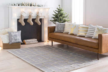 Festive living room with a beige Wadesboro Area Rug, brown leather sofa, and decorated fireplace. Roomscene-Rectangle