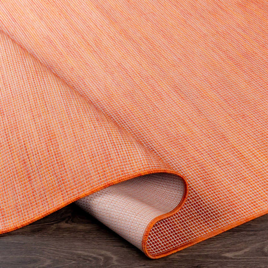 Close-up of the textured weave and backing of the orange Weobley Area Rug. Fold