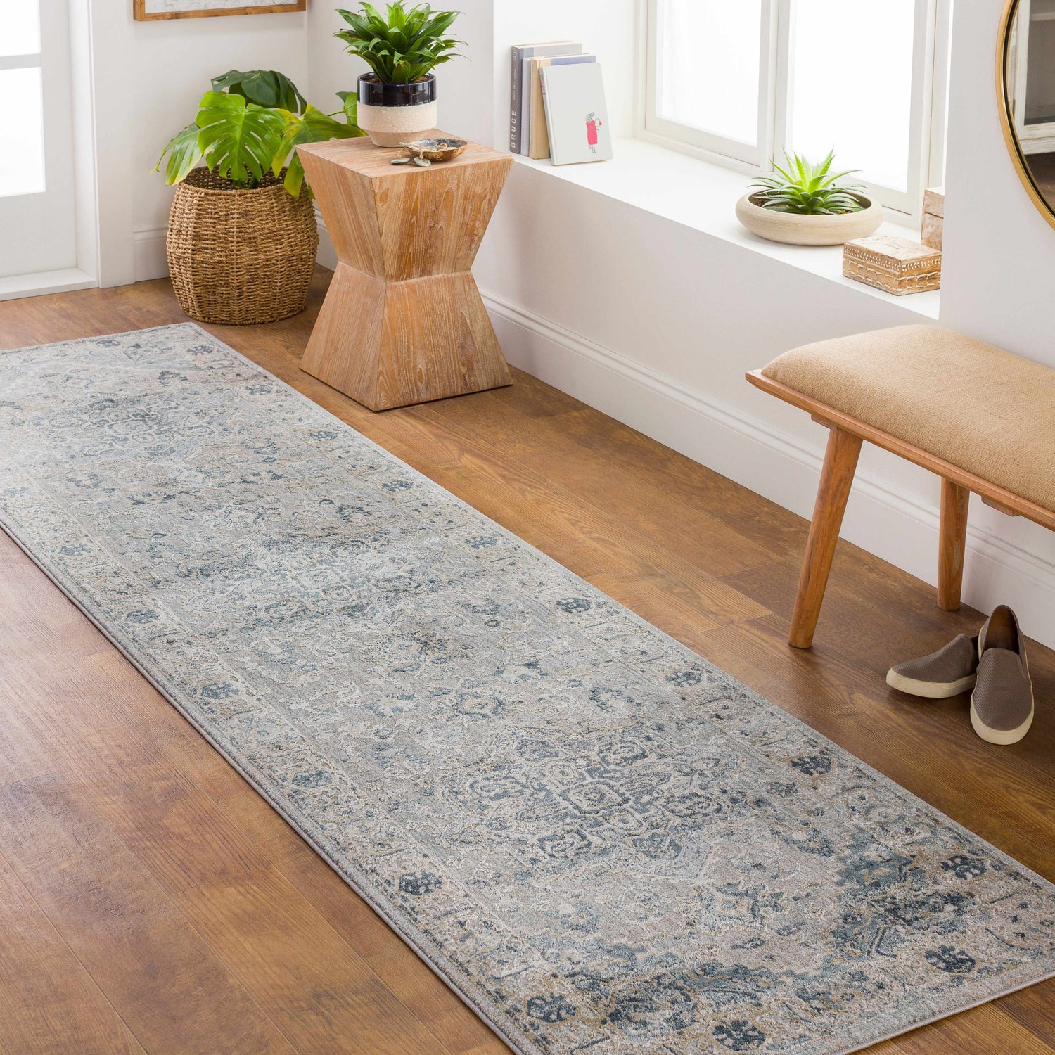 Entryway scene with a Whangamata Thick Luxe Boutique Rug runner in light gray and blue, with a wooden bench, plants, and light wood floors. Roomscene-Runner