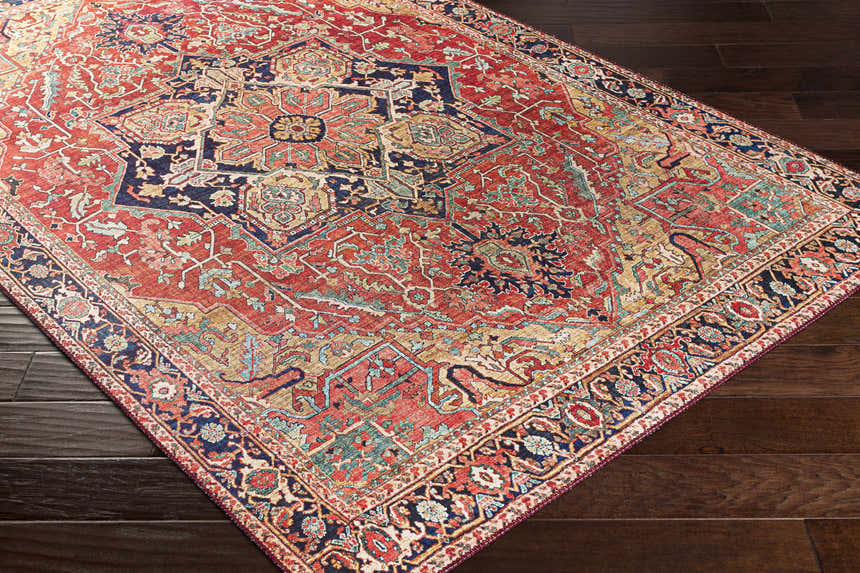 Close-up of the Whittingham Area Rug, a machine-woven rug with a traditional oriental pattern in brick red, navy, and tan. Corner