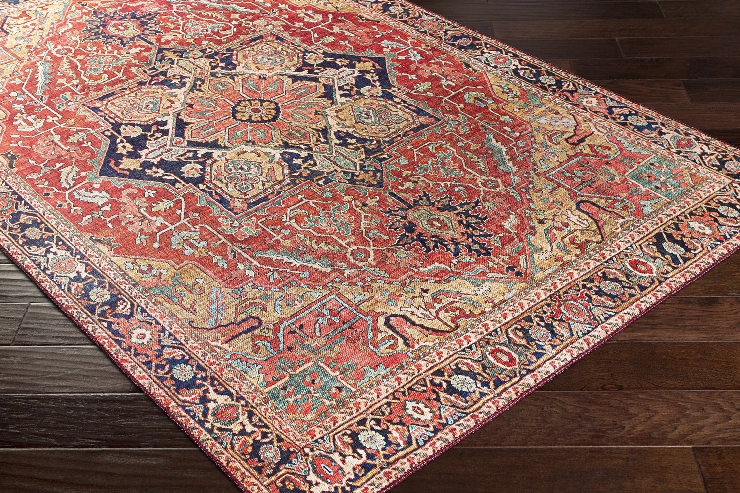 Close-up of the Whittingham Area Rug, a machine-woven rug with a traditional oriental pattern in brick red, navy, and tan. Corner