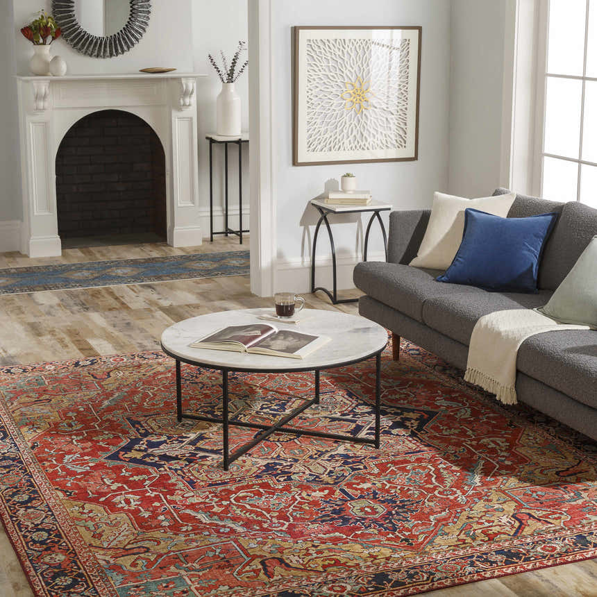 Living room scene with a brick red and navy Whittingham Area Rug, gray sofa, and marble coffee table. Roomscene-Rectangle
