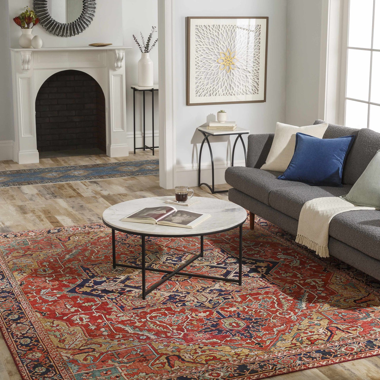 Living room scene with a brick red and navy Whittingham Area Rug, gray sofa, and marble coffee table. Roomscene-Rectangle