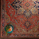 Close-up of the Whittingham Area Rug, showcasing its brick red, cream, and navy bohemian-style pattern and soft polyester texture. Styleshot