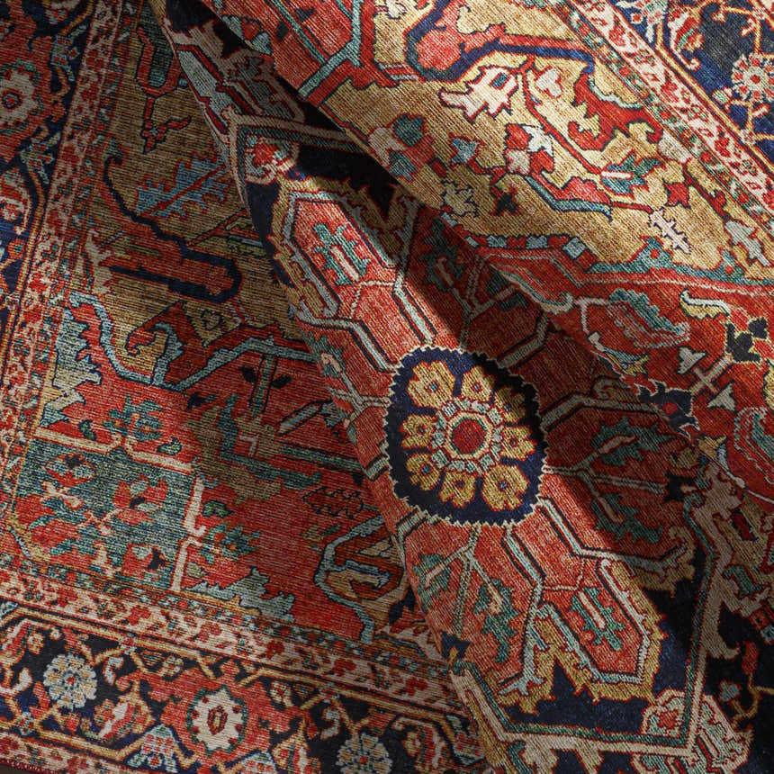 Close-up of the Whittingham Area Rug, a traditional rug in brick red, cream, navy, and brown with an ornate oriental pattern. Fold