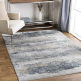 Living room scene with a neutral chair and the Whyalla Misty Thick Luxe Rug in shades of gray, taupe, and white. Roomscene-Rectangle