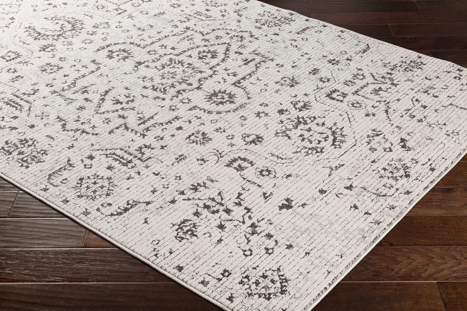 Close up of Willowbrook Area Rug in charcoal, gray, light beige, and medium gray with a vintage, oriental-inspired pattern. Corner