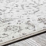 Close-up of the Willowbrook Area Rug showing its light beige base and charcoal gray vintage-style pattern and texture. Texture