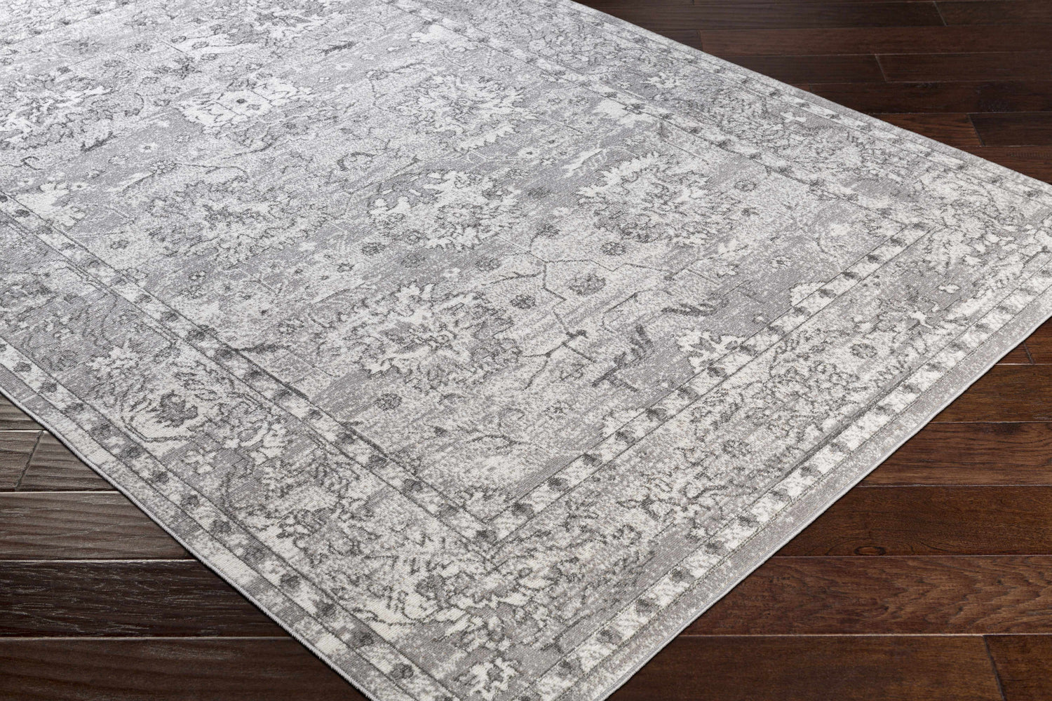 Close up of the Winstonville Clearance Rug, a traditional gray and white rug on dark wood floors. Corner