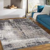 Living room scene with a Witchford Abstract Charcoal Thick Rug, blue sofa, fireplace, and wood floors. Roomscene-Rectangle