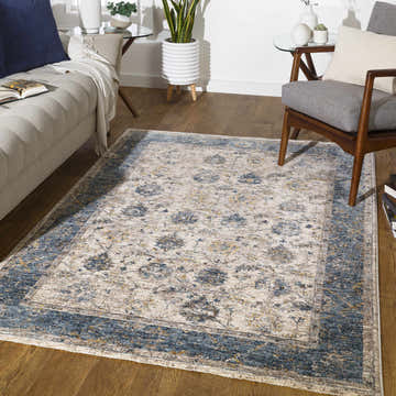 Living room scene with a Wilkie Blue Persian Rug, light gray sofa, and mid-century modern chair on a wood floor. Roomscene-Rectangle