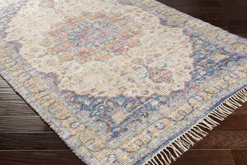 Close-up of Wallburg rug. Hand woven jute rug with light blue, purple, tan, and yellow floral pattern and tassels. Corner