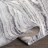 Close-up of the Walloon Gray Marble Thick Rug showing its charcoal, gray, and ivory marbled design and woven texture. Fold