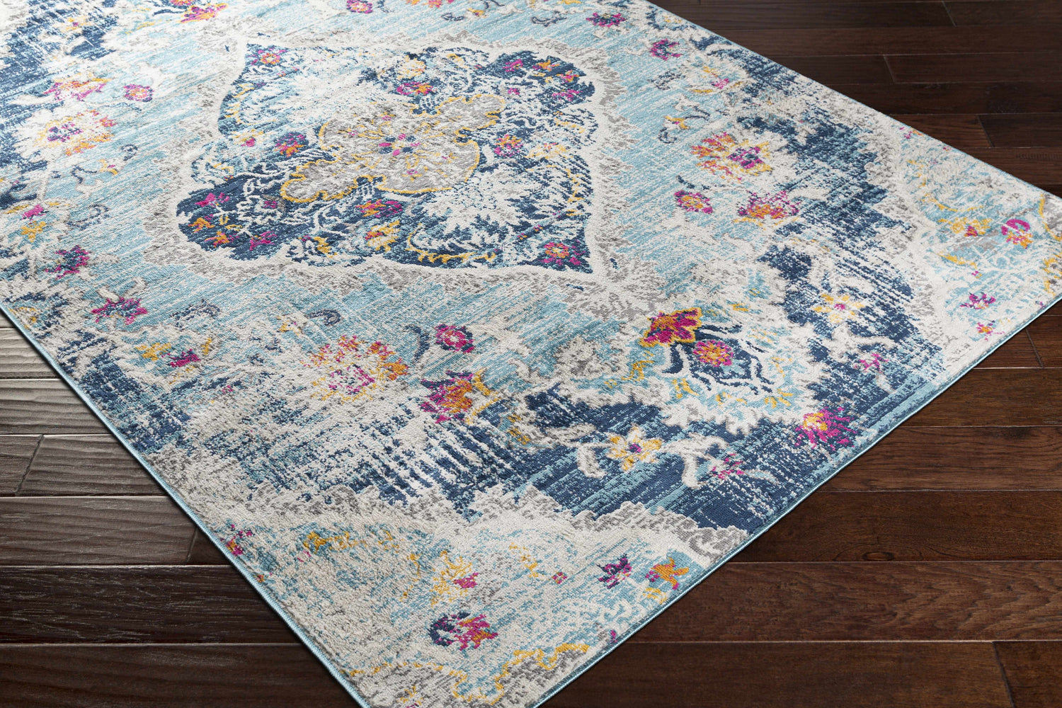 Close-up of the Wallsburg Blue Area Rug showing its bohemian floral pattern and colors like blue, orange, fuchsia, and gray. Corner