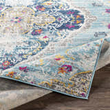 Close-up of the Wallsburg Blue Area Rug, showcasing its bohemian pattern, light blue, navy, and fuchsia colors. Fold