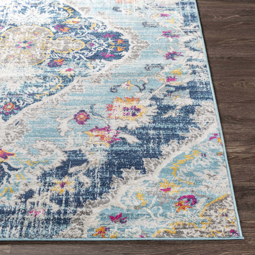 Close-up of the Wallsburg Blue Area Rug. Features burnt orange, fuchsia, gray, and light blue floral pattern. Front