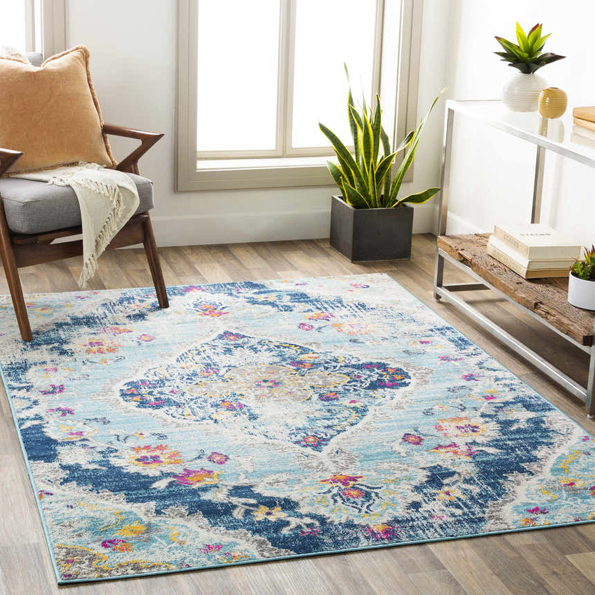 Living room scene with a Wallsburg Blue Area Rug, gray chair, wood floors, and natural light. Roomscene-Rectangle