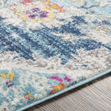 Close-up of the Wallsburg Blue Area Rug showing its texture, blue, gray, white, fuchsia, and mustard colors, and machine-woven construction. Texture