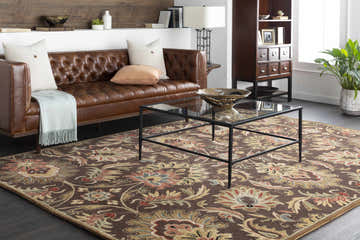 Living room scene with brown leather sofa and Chesterton 1028 Hand Tufted Brown Wool Rug featuring a traditional floral pattern. Roomscene-Rectangle