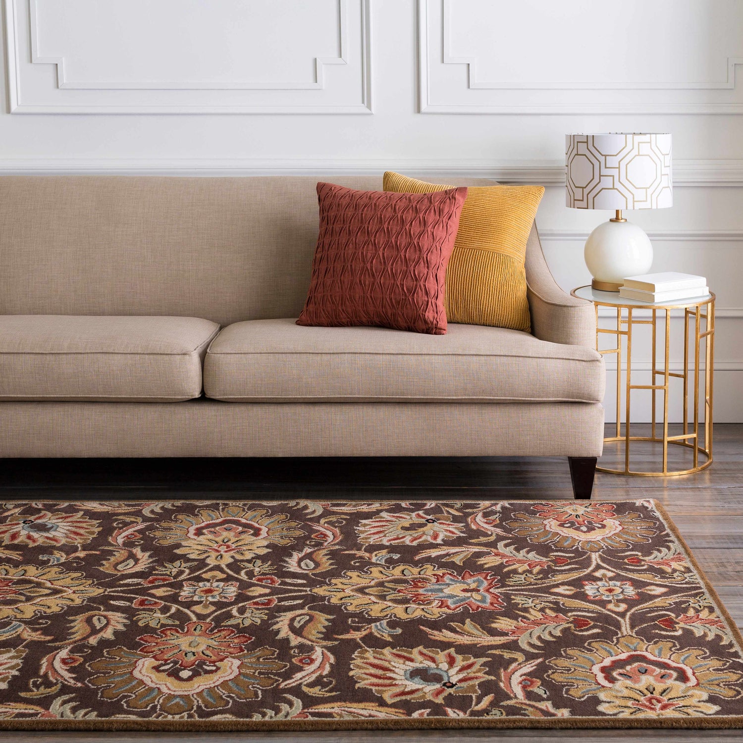 Living room scene with a Chesterton 1028 brown wool rug, beige sofa, brick red and gold pillows, and a gold side table. Roomscene-Rectangle