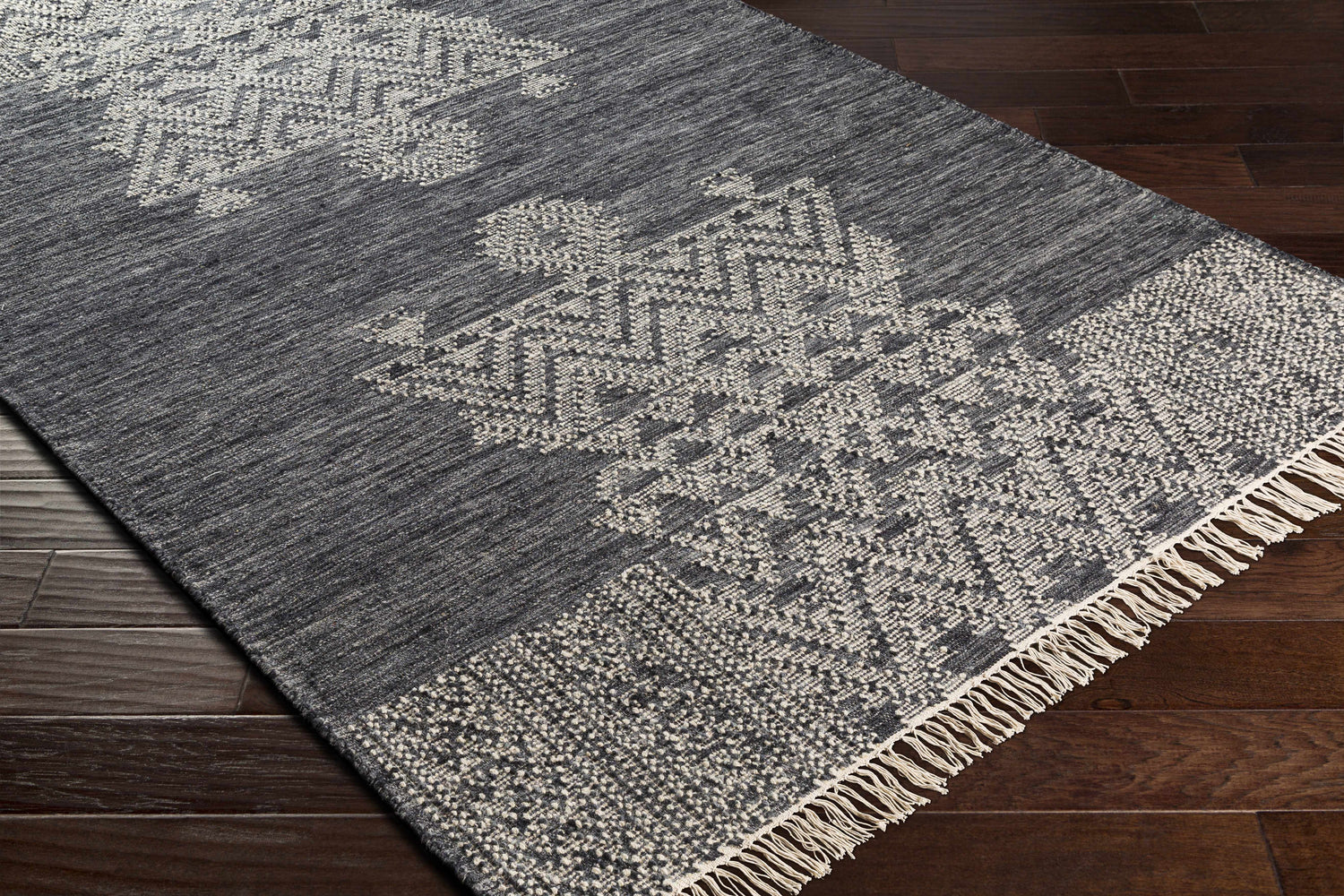 Close-up of the Warrawee Wool Rug. Ink blue rug with cream geometric patterns and fringe detail. Hand woven texture. Corner