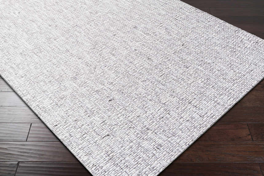 Close-up of the Westoning Area Rug showing its light gray, off-white, and charcoal textured design on dark wood floors. Corner