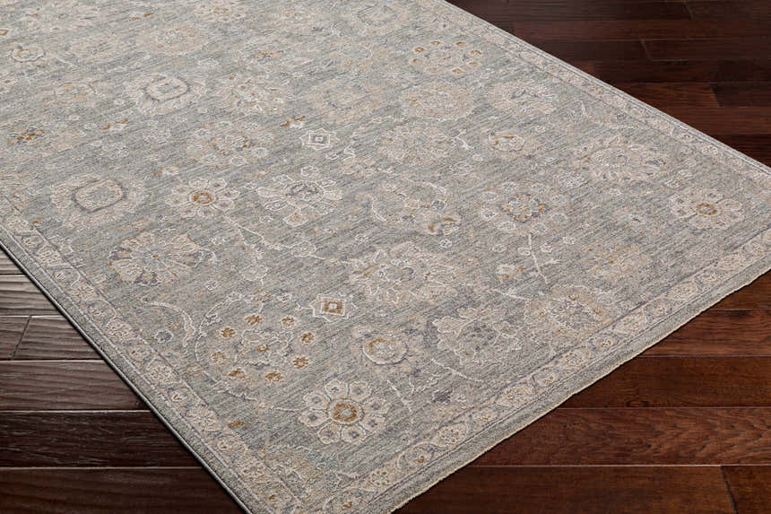 Close-up of the Wurtulla Thick Luxe Statement Rug. The rug has a traditional floral pattern and colors of dusty sage, beige, and brown. Corner