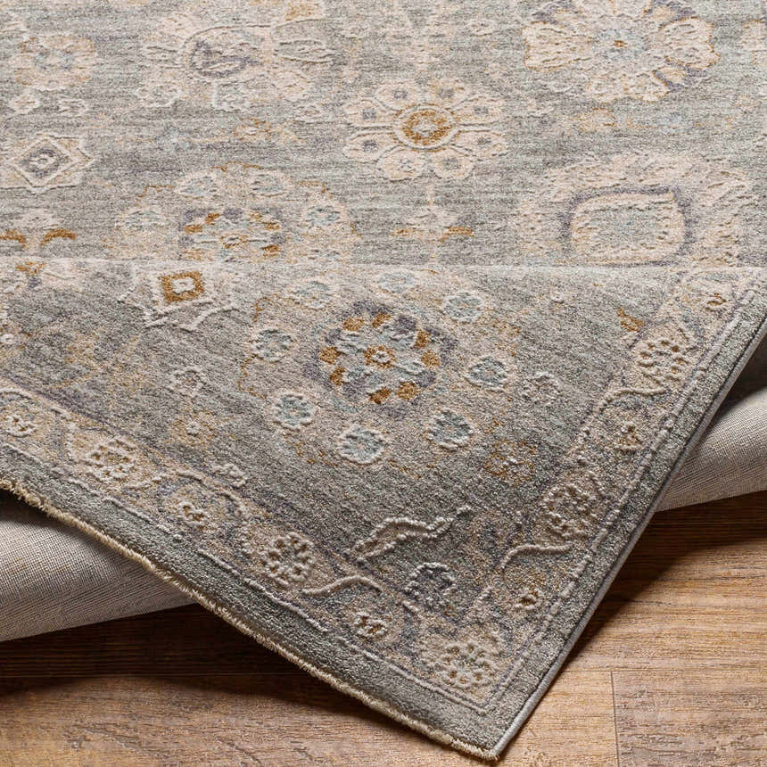 Close-up of the Wurtulla Thick Luxe Statement Rug, showing its light beige, gray, and denim traditional floral pattern and texture. Fold