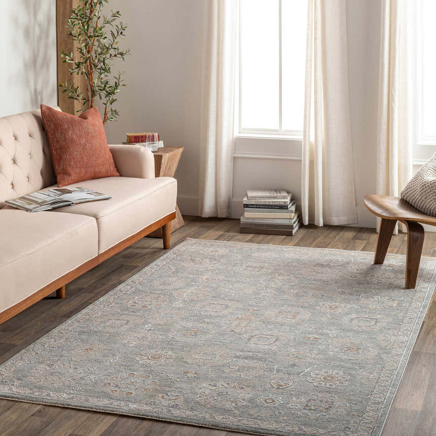 Living room scene with a Wurtulla Thick Luxe Statement Rug in brown, denim, and sage colors. Features a sofa, wood floors, and natural light. Roomscene-Rectangle